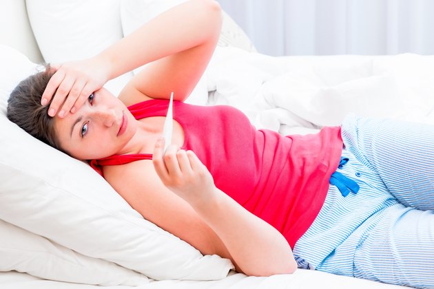 ill girl with a thermometer lying in bed