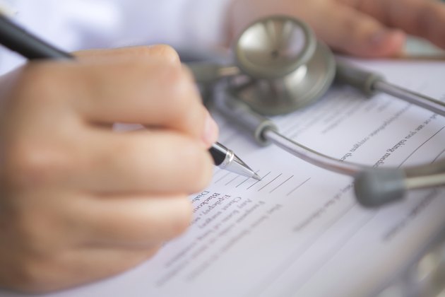 Hand of doctor writing on prescription