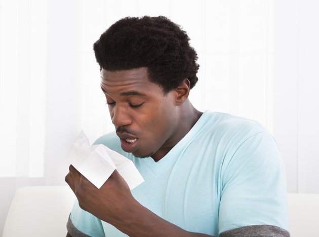 Young Man Blowing His Nose In A Tissue