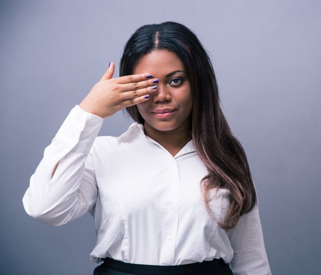 African businesswoman covering one eye with hand