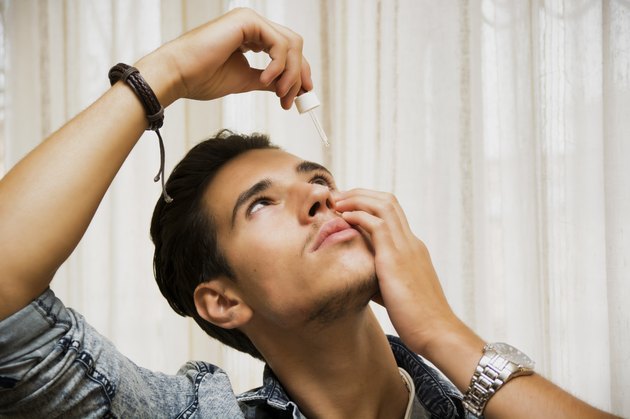 Handsome young man dropping medicine in his eye
