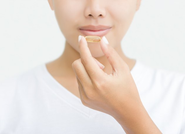 close up woman taking vitamin capsule for healthy
