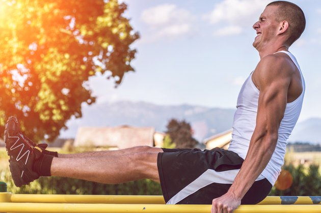 Muscular man workout out on bars