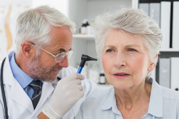 Doctor examining senior patient's ear