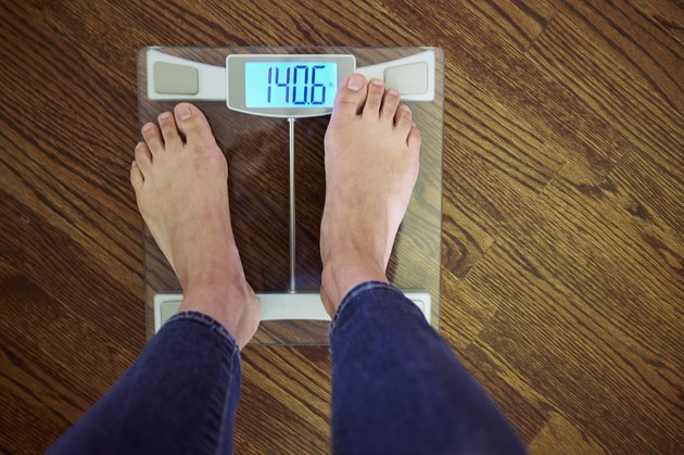 Woman standing scales with digital display, low section, elevated view