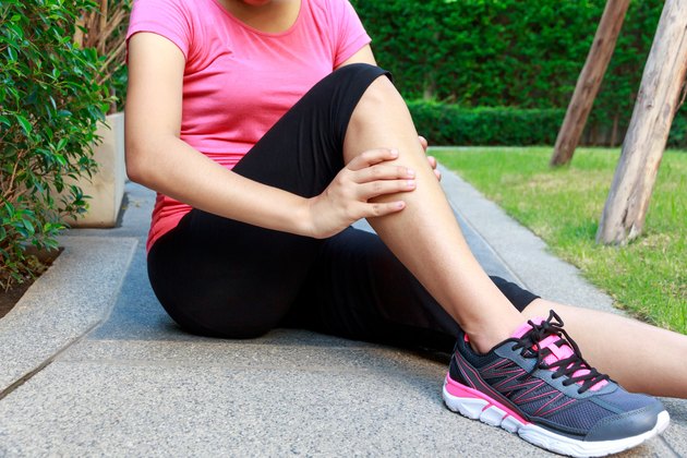 Asian sporty woman leg pain or calf muscle while jogging