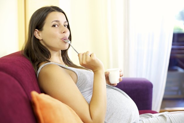 愉快的孕妇在家里吃白酸奶