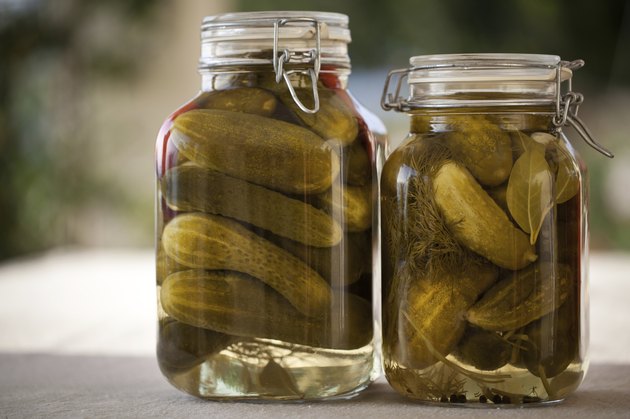 Glass jars of homemade canned cucumbers on the outdoors kitchen