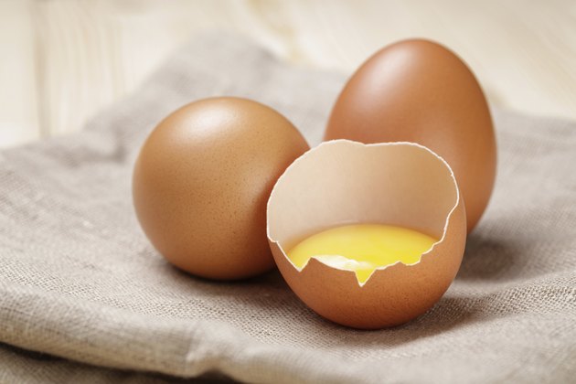 raw chicken eggs one open with yolk