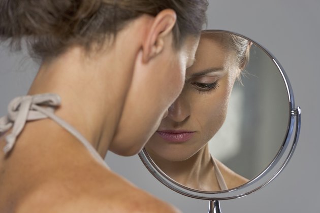 stressed young woman looking in mirror