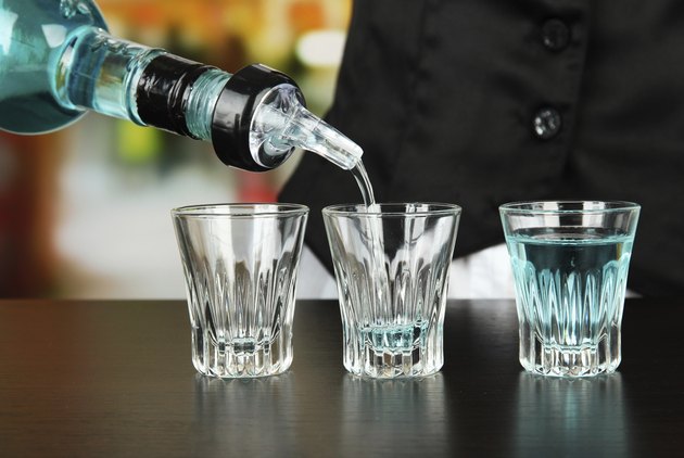 Barmen hand with bottle pouring beverage into glasses