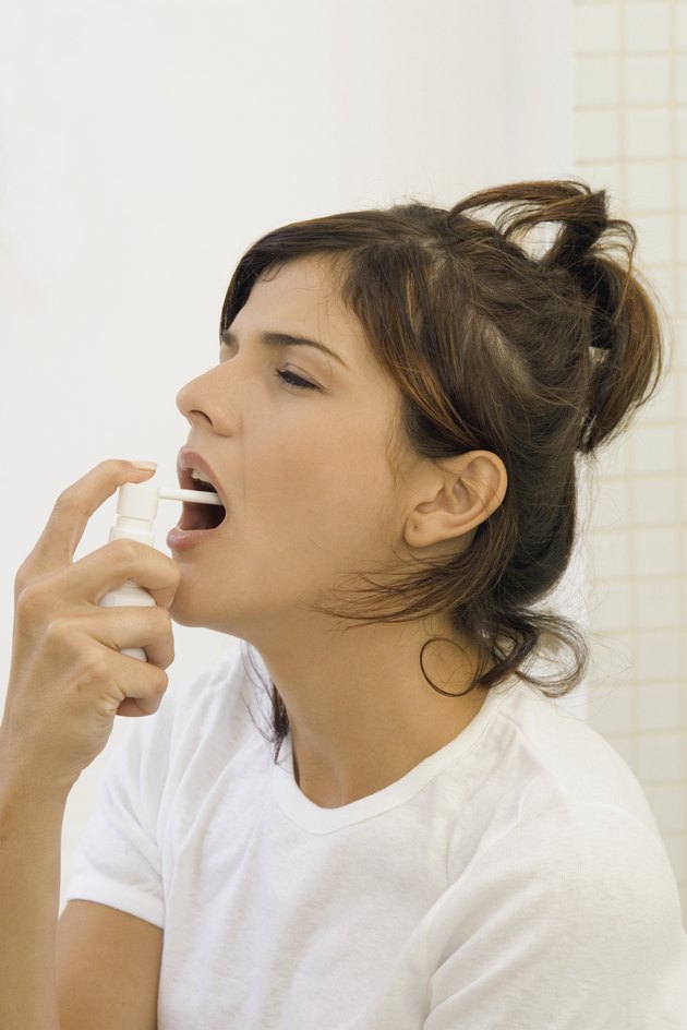 Young woman spraying mouth spray, close-up