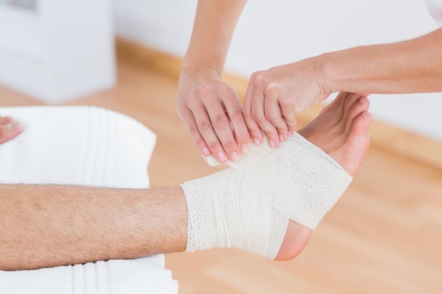 Doctor bandaging her patient ankle