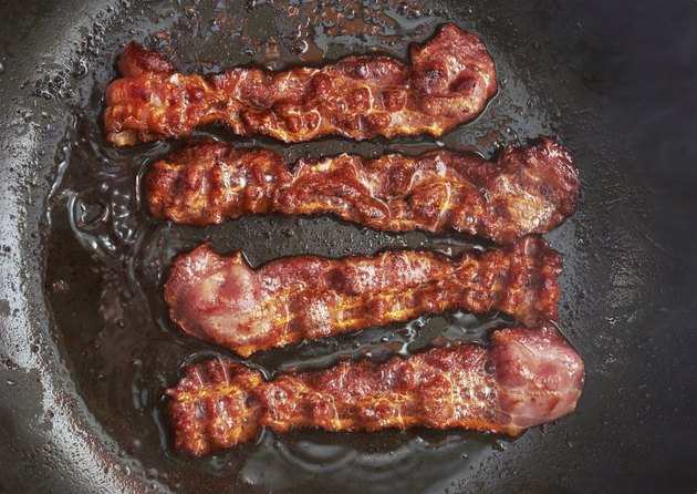 Bacon slice being cooked in frying pan