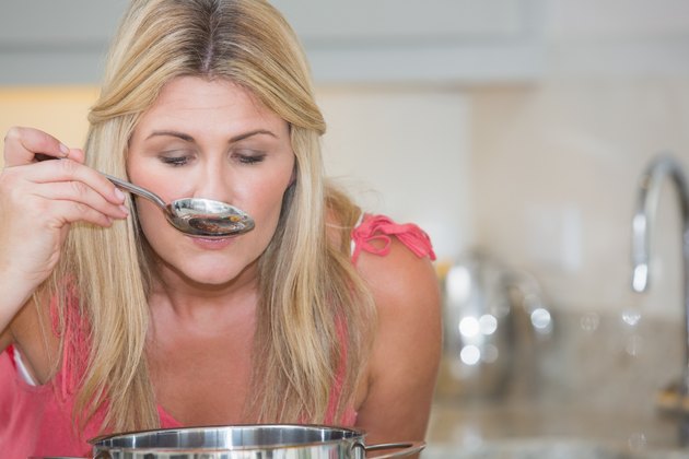 Young woman tasting food in kitchen