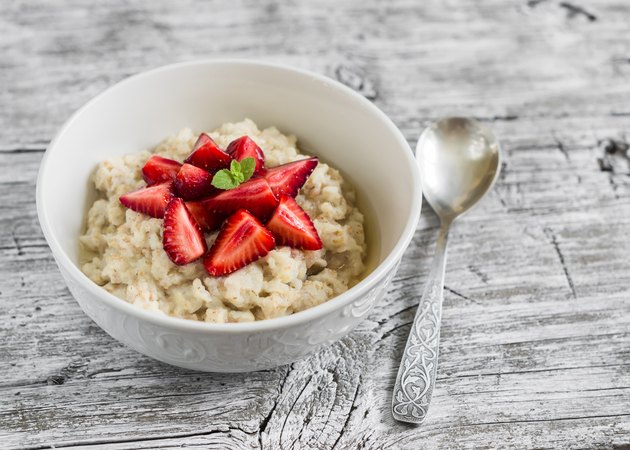 oatmeal with honey and strawberries in a white bowl