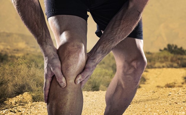 sportsman athletic legs holding knee in pain suffering muscle injury
