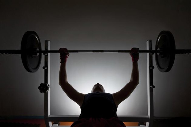 Man weightlifter at the gym, lifting weights on a benchpress