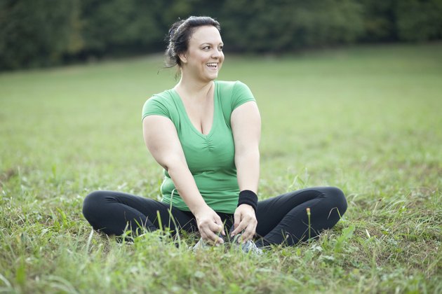Cheerful plus sized woman stretching in the park