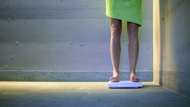 Young woman on bathroom scales, low section