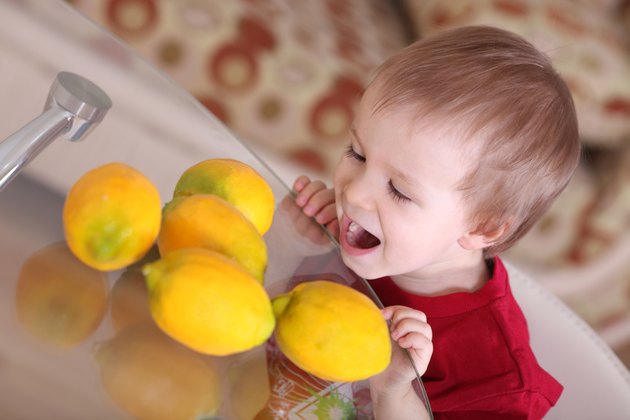 Blond hair boy eating and playing with lemons
