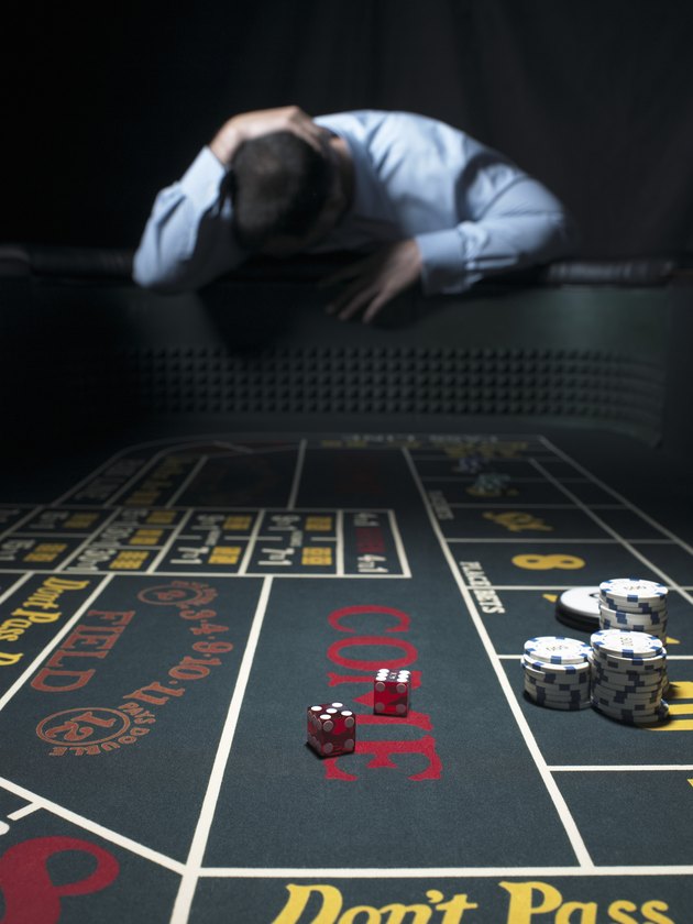 Man slumped at craps table, holding head (focus on table)