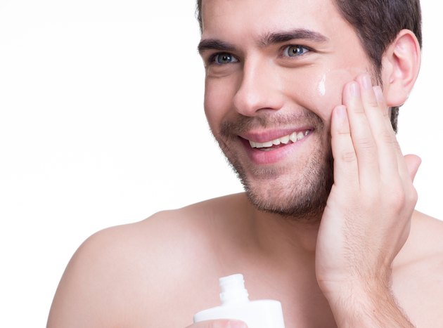 Young happy man applying cream.