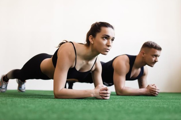 Man and woman doing plank exercises at the gym