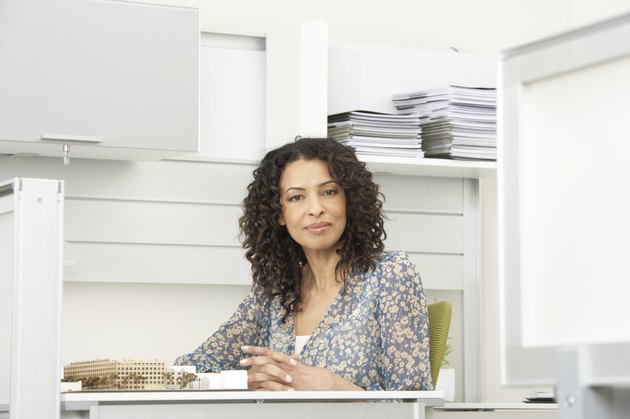 Mature businesswoman sitting at desk, smiling, portrait