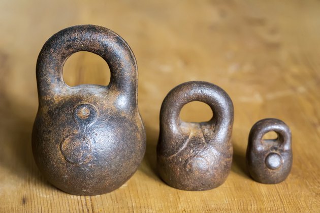 Three small calibration weights on wooden background