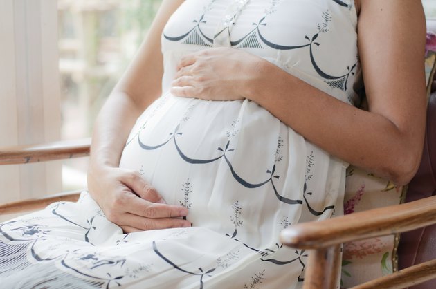 pregnancy woman sit on a chair near the window