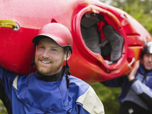 Two men carrying kayak, outdoors, portrait