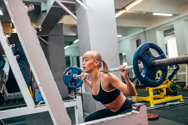 fitness woman doing barbell squats in a gym
