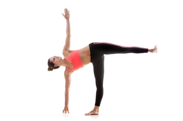 Sporty yoga girl on white background in ardha chandrasana (Half Moon Pose)
