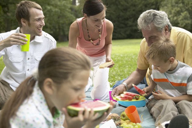 Three generational family picnicking in park, smiling
