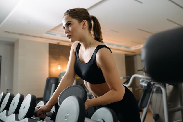 Beautiful woman take a dumbbell in gym
