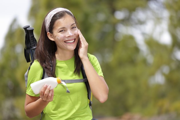woman hiking putting sunscreen