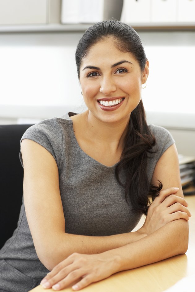 Businesswoman sitting at desk in office, portrait