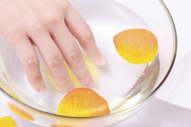 Female hand soaking glass bowl water. Manicure spa beauty salon.