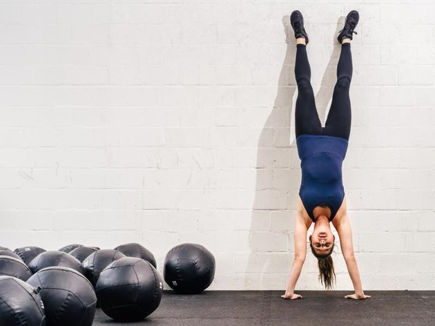 Photo of a young fit woman doing a handstand exercise at a gym.