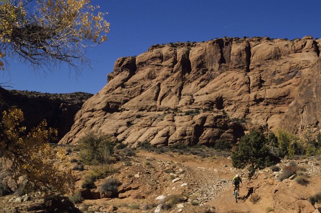 Mountain biker on trail in front of cliff, elevated view