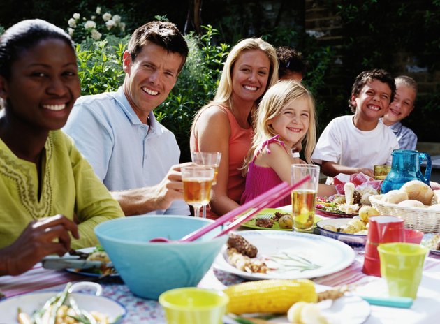 Group of people at lunch table outdoors, smiling, portrait