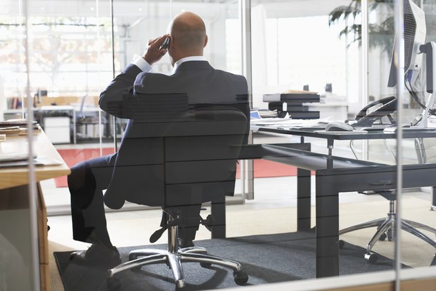 Businessman using telephone in office, rear view
