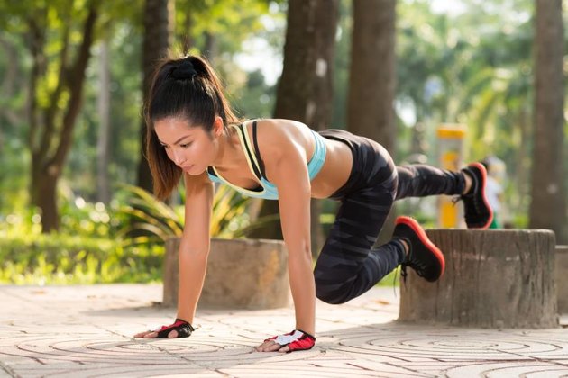 young woman doing plank exercise outdoors