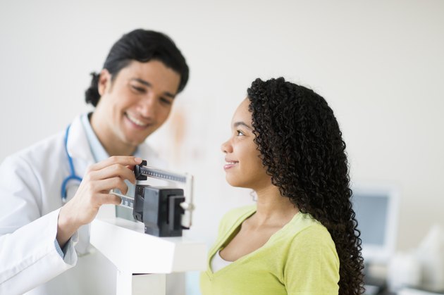 USA, New Jersey, Jersey City, Doctor weighing female patient (10-11)