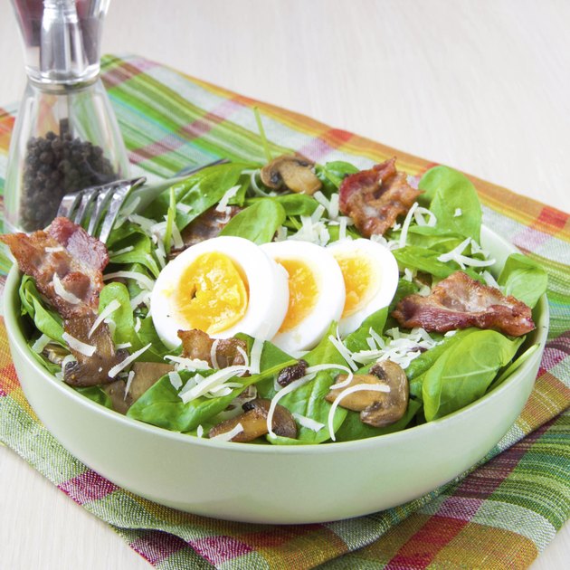Tasty salad with spinach, bacon, champignon mushrooms, cheese, egg