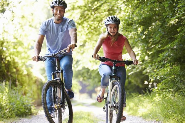 Couple On Cycle Ride In Countryside Smiling At Camera