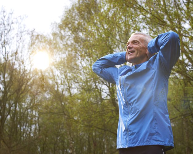 Mature Male Runner Stretching Arms In Park