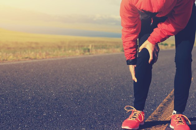 woman runner hold her injured leg on road