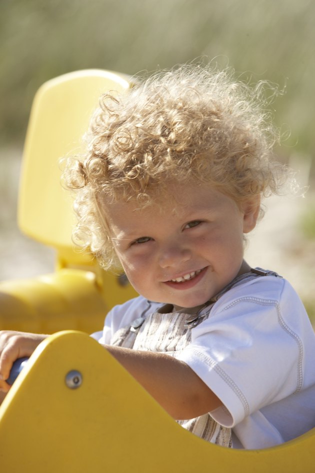 Toddler boy (2-4) sitting in playground ride, smiling, portrait